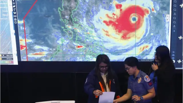 Miembros de un equipo utilizan una fotocopiadora frente a una pantalla donde se muestran detalles de la trayectoria del tifón Mangkhut en la ciudad de Quezon, al este de Manila, Filipinas, el 13 de septiembre de 2018.