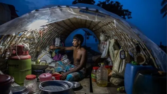 बांग्लादेश में नाव पर खाना बनाता व्यक्ति