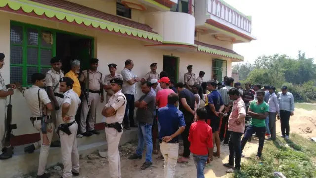 पीड़िता के घर के बाहर खड़े लोग और पुलिसकर्मी