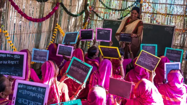 زنان در کلاس تخته سیاه های خود را بالا گرفته اند