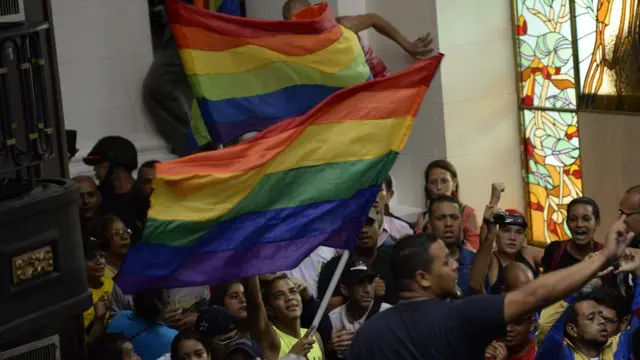 Grupos de manifestantes con banderas arcoiris