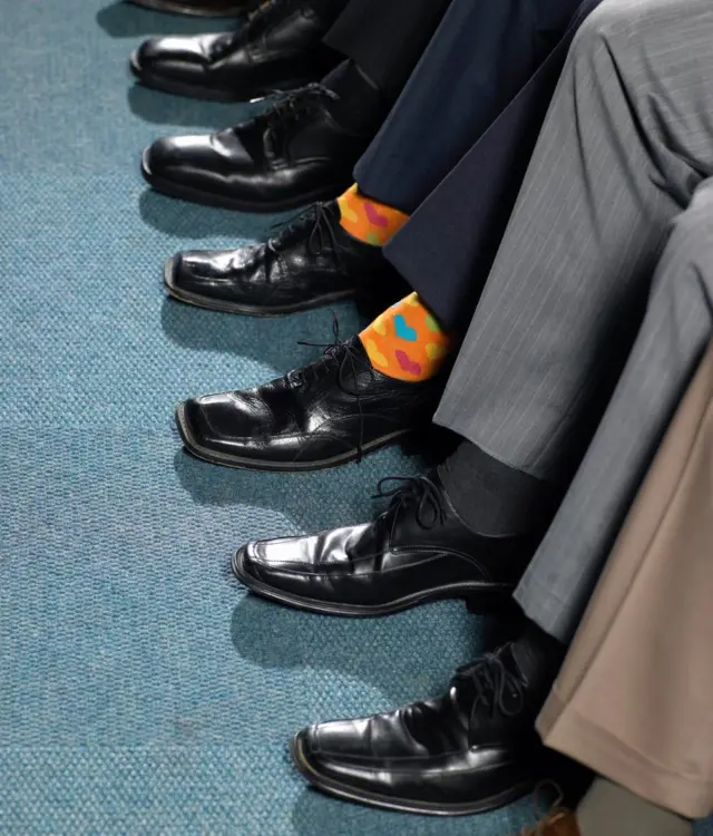 Piernas de hombres y uno con medias de colores