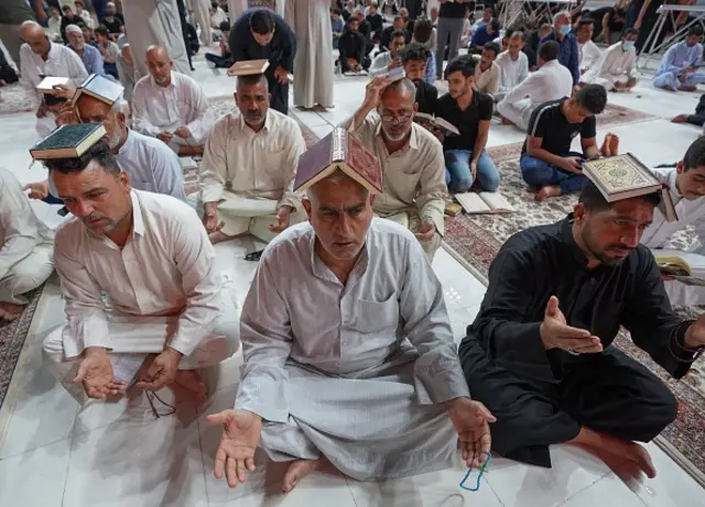 Worshippers place the Koran, Islam's holy book, on their heads during prayer rituals of Laylat al-Qadr (Night of Destiny) which marks the night in which the holy Koran was first revealed to the Prophet Mohammed, at the Imam Ali shrine in the holy Iraqi city of Najaf, on May 1, 2021. (Photo by Ali NAJAFI / AFP) (Photo by ALI NAJAFI/AFP via Getty Images)