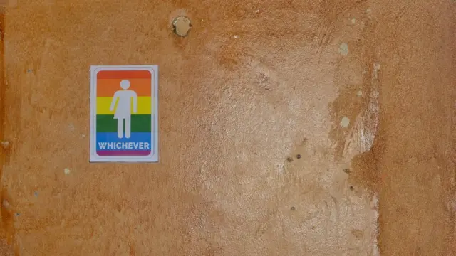 A sign is attached to a wall as people take part in the LGBT community pride Parade in the streets of the Namibian Capitol in Windhoek.