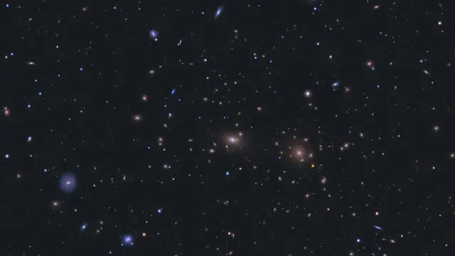 A star field with many galaxies visible, both blue and white. They are somewhat clustered towards the centre of the image.