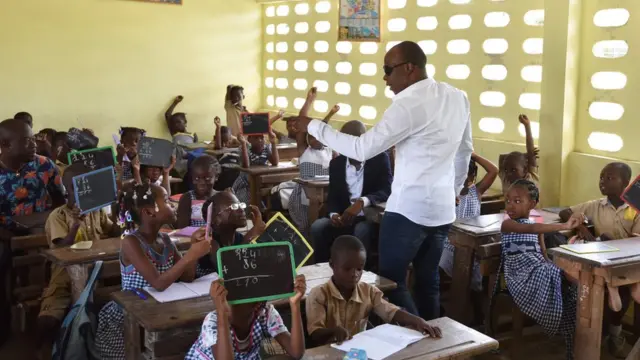 MMoja wa wanamuziki wa bendi ya Ivory Coast "Magic System" inayojumuisha mwanamuziki A"Salfo (Kulia), akikutana na wanafunzi wa shule