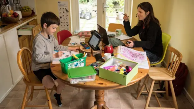 Uma mulher e o filho na mesawild spin cassinocasa; enquanto ela trabalha, ele desenha