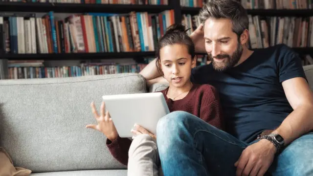 Отец и дочь обсуждают что-то, глядя в планшет