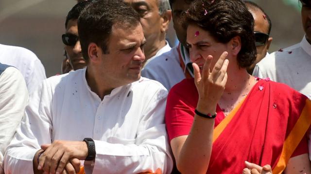 Indian National Congress party president Rahul Gandhi (L) and his sister Priyanka Gandhi (R) wave during a road show before filing his nomination for the upcoming general election at the district collector's office in Amethi on April 10, 2019.