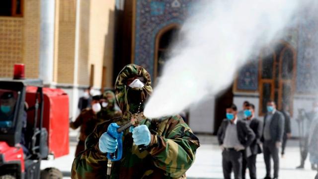 Membro da defesa civil do Iraque lança desinfetantes na grande mesquita de kufa