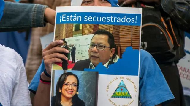 Manifestante con una foto de Miguel Mora y Lucía Pineda Ubau