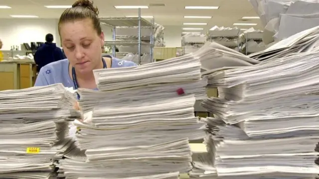 Una mujer detrás de varias pilas de papeles