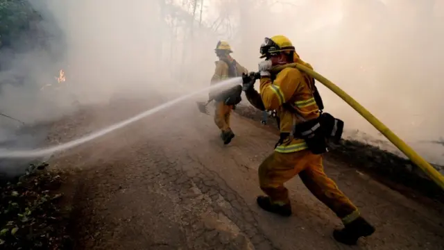 Firefighter holds large hose in Mendocino Complex Fire