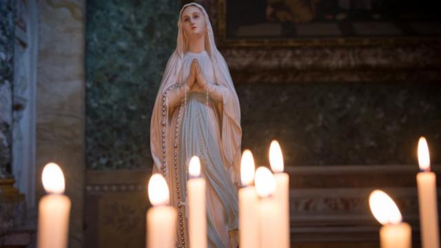 Estátua de Maria Madalena ao lado de velas