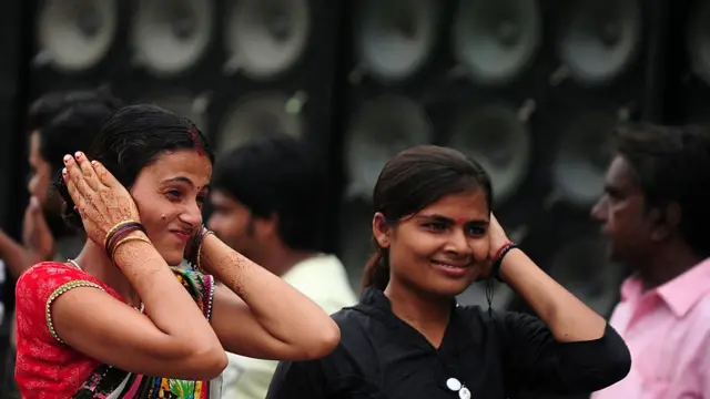 Mujeres se tapan los oídos.