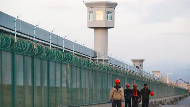 Workers walk by the perimeter fence of what is officially known as a vocational skills education centre in Dabancheng in Xinjiang Uighur Autonomous Region, China September 4, 2018.