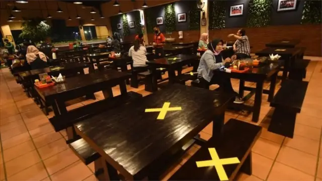 Pengunjung menyantap hidangan di antara meja yang diberi tanda silang di salah satu restoran di Srengseng Sawah, Jakarta Selatan, Kamis (09/04/20).