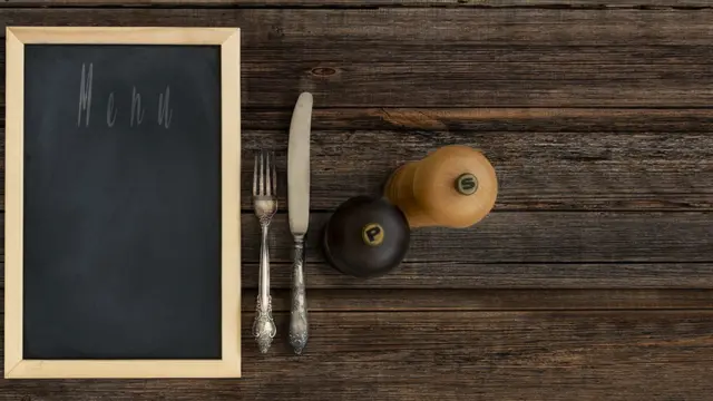 Sobre la mesa, sal, pimienta, cubiertos y un menú.