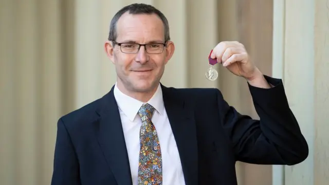 จอร์น โวลันเธน ชูเหรียญจอร์จ เมดัล