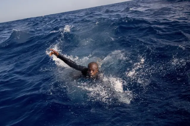 A migrant tries to board a boat of the German NGO Sea-Watch in the Mediterranean Sea on November 29, 2017. During a shipwreck, five people died, including a newborn child. According to the German NGO Sea-Watch, which has saved 58 migrants, the violent behavior of the Libyan coast guard caused the death of five persons.