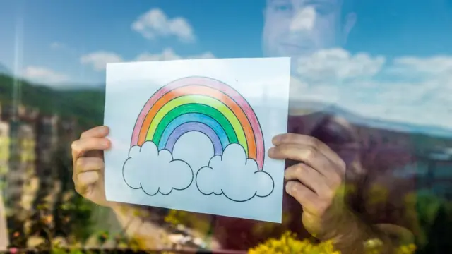 Hombre sosteniendo arcoíris en la ventana