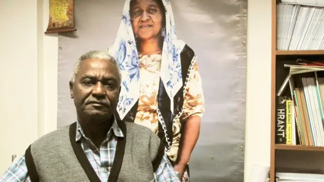 Bir fotoğraf önünde oturan Afrika kökenli adam