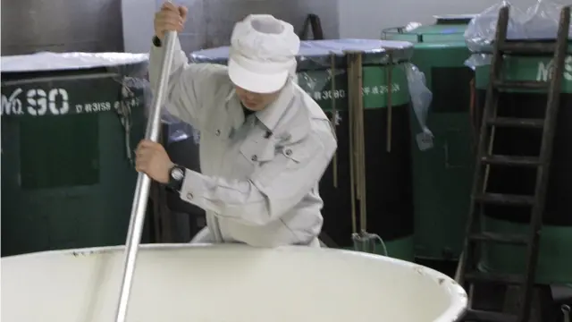 Empleado revolviendo algo en una gran olla