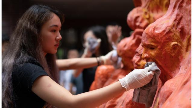 Students clean the "Pillar of Shame" statue, an art piece dedicated to the victims of the 1989 Beijing Tiananmen Square massacre,