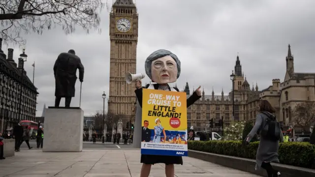 Manifestante com máscaragrêmio x novorizontino palpitesTheresa May durante protesto conta o Brexit