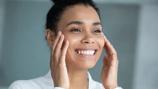 Mulher sorrindo com as mãos no rosto