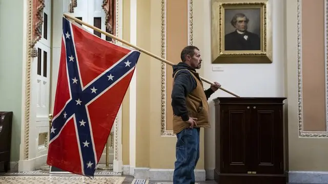 پرچمی که این مرد هنگام یورش به کنگره ایالات متحده آمریکا بر دوش گرفته بود، پرچم نبرد کنفدراسیون آمریکا است. کشوری متشکل از ایالت‌های جنوبی آمریکای امروزی که موافق برده داری بودند