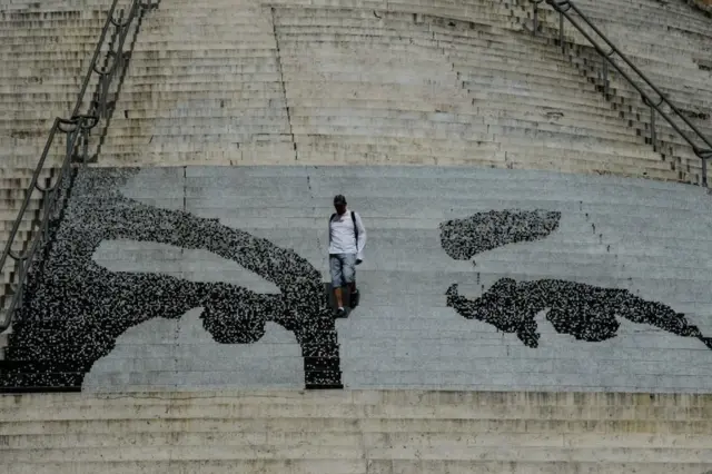 Un hombre baja las escaleras de la plaza del Calvario de Caracas, que tiene pintada la mirada del fallecido presidente de Venezuela, Hugo Chávez.