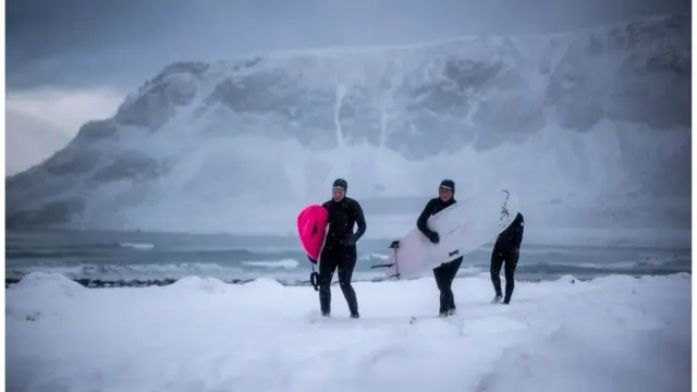 Люди идут по берегу с досками