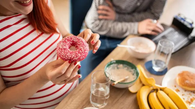 Femme enceinte mangeant un beignet délicieux à la maison.