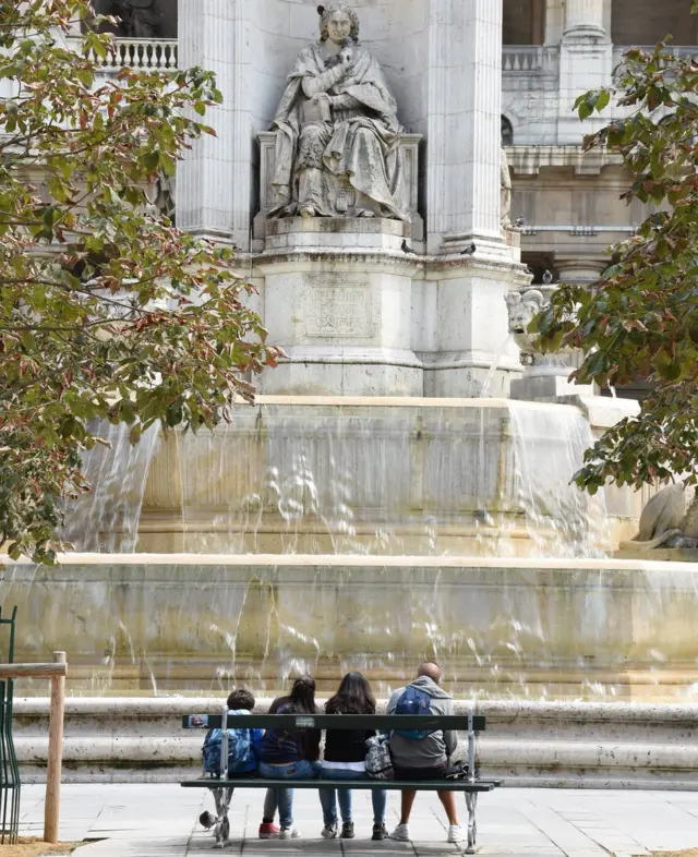 Estudiantes al pie de una estatua.