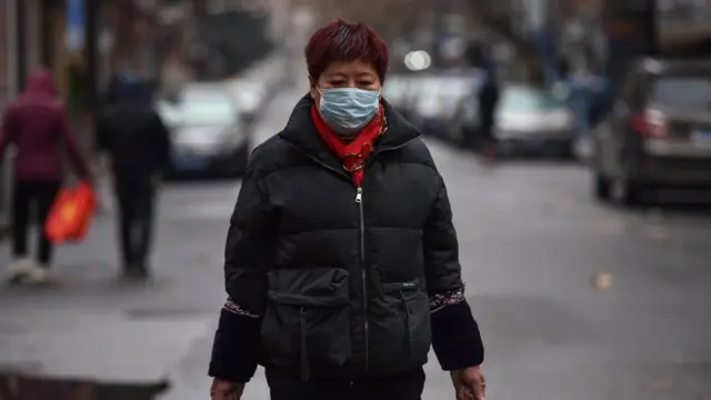 A woman wearing a protective facemask returns from a market in Wuhan