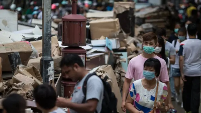 戴著口罩的澳門居民走過堆積如山的災後垃圾（25/8/2017）