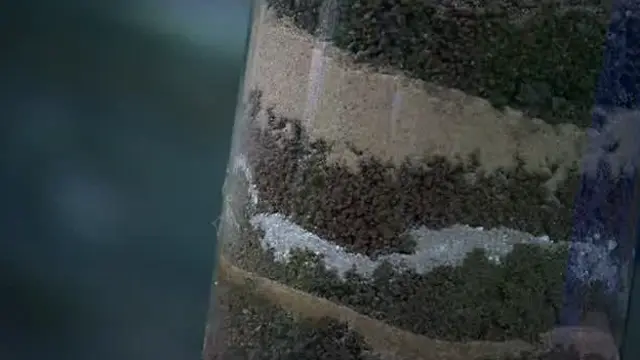 Recipiente de vidrio con tierra de diferentes colores.