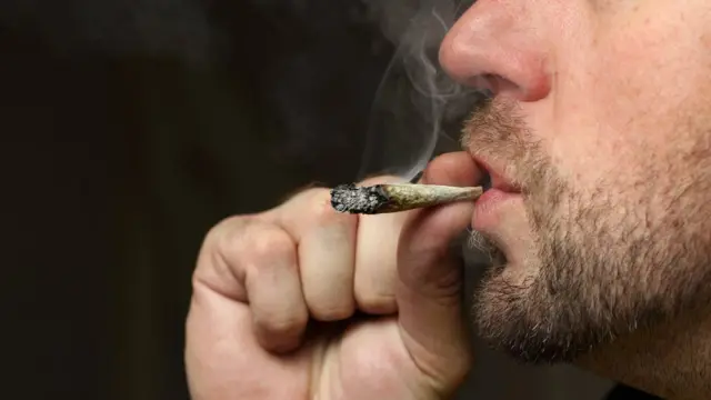 Hombre con barba fumando un porro.