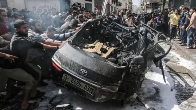 سيارة مدمرة يتجمع حولها حشد من الأشخاص