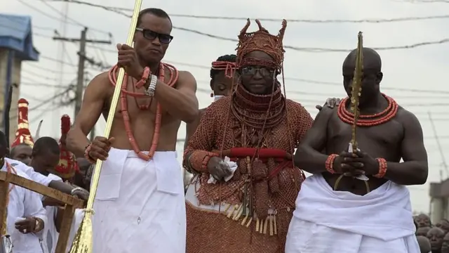Le nouveau 40e Oba, ou roi, du royaume du Bénin, Oba Ewuare II (C), marche sur un pont en bois assisté par des aides du palais pour accomplir le rite lors de son couronnement à Benin City, au centre-ouest du Nigeria, le 20 octobre 2016
