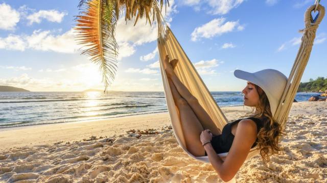 Mulher descansando na redewhatsapp do sportingbetuma praia