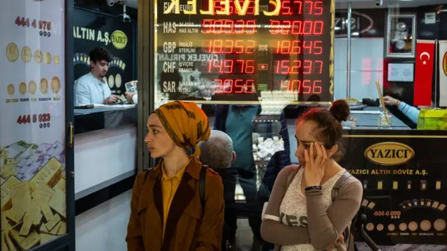 People stand next to a currency exchange office at Istanbul's Grand Bazaar on May 05, 2022 in Istanbul, Turkey. Inflation soared to nearly 70% (69.97%) over one year in April in Turkey, the highest since February 2002, according to official figures released on May 5.