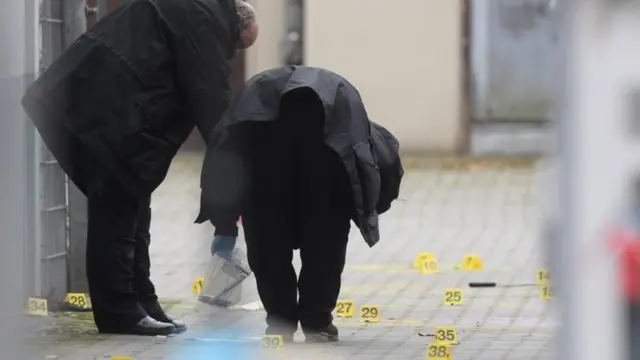 Os investigadores se curvam sobre marcadores no solo durante as investigações na cena do crime em Berlim, Alemanha, 26 de dezembro de 2020
