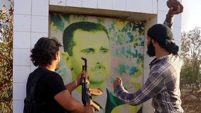 Syrian opposition fighters damage a portrait of Bashar al-Assad in Deraa (file photo)