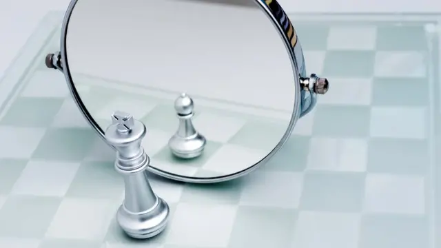 Silver chess king imagining itself as a pawn