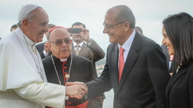 Fotografia colorida mostra o papa Francisco, um idoso vestidoapostas esportivas online betanobranco, dando a mão para Geraldo Alckmin, um homem brancoapostas esportivas online betanoóculos e terno