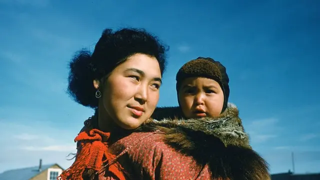 CIRCA 1955: A portrait of an Inuit women and her baby on her back in Unalakleet,Alaska.