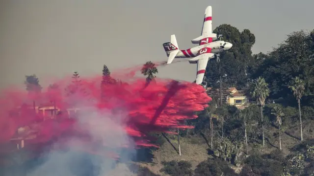 Una avioneta sobrevuela el lujoso barrio de Bel Air, en Los Ángeles, California, para extinguir el incendio Skirball