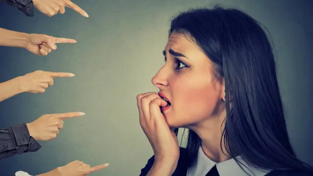 Una mujer señalada por varias manos.